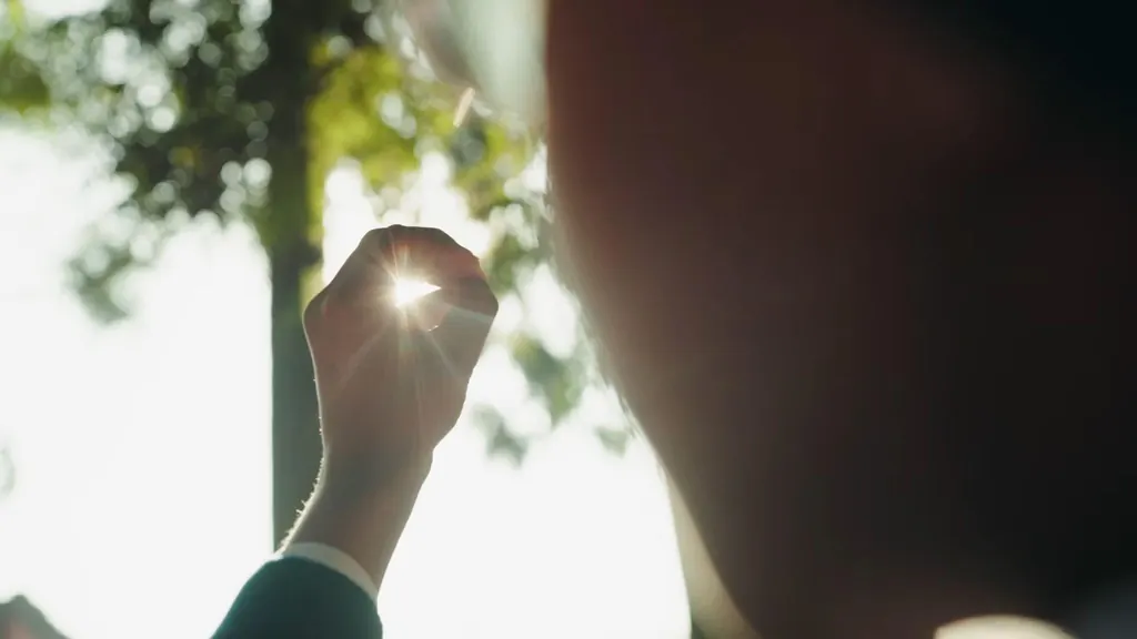 Sunlight breaking through a hand raised against the sky
