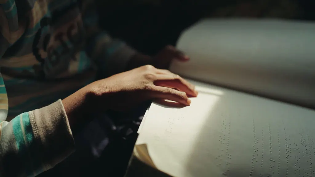 Fingers reading a page of braille