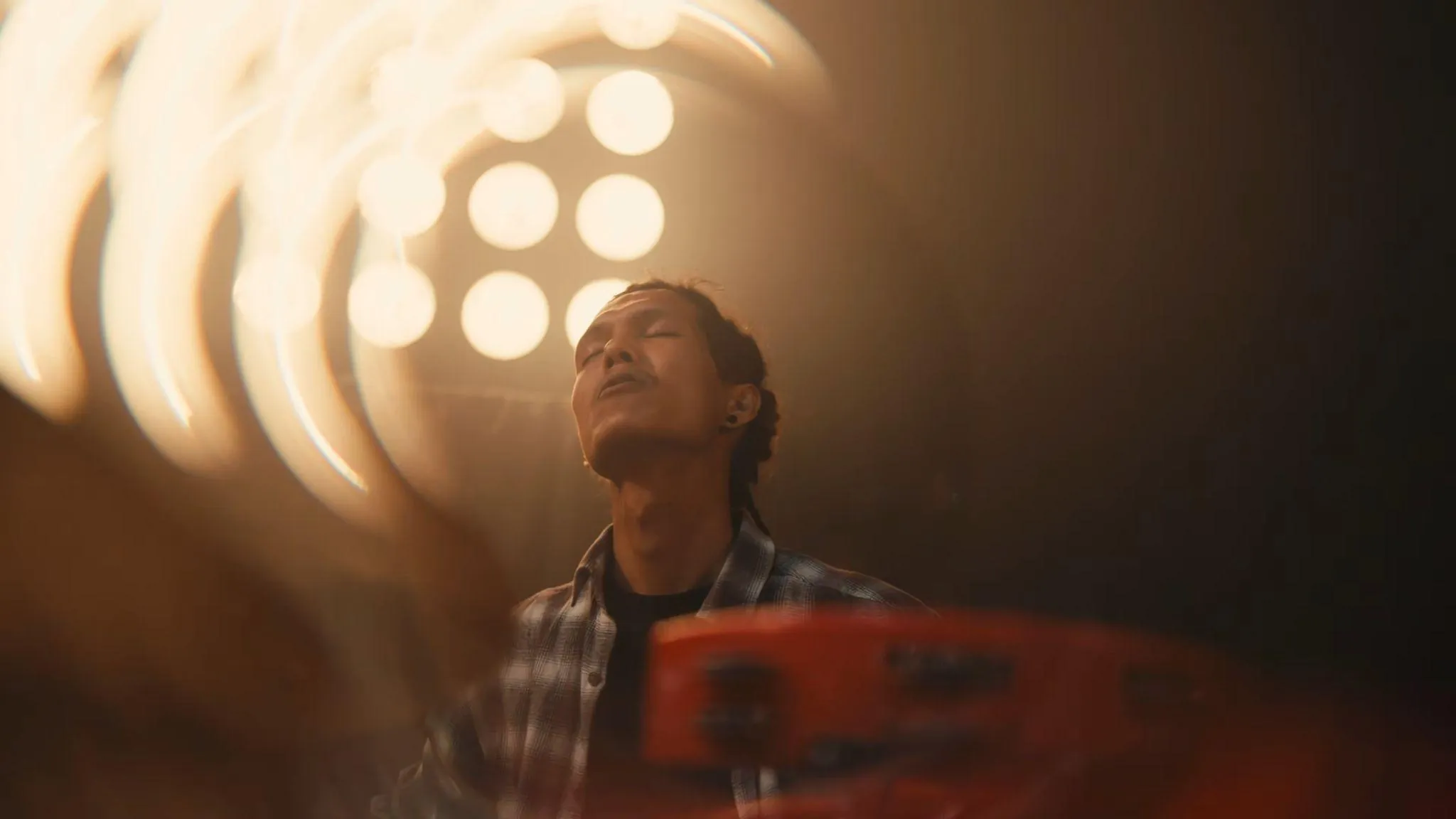 A musician singing with eyes closed under warm stage lights, from Madhur Jhankaar