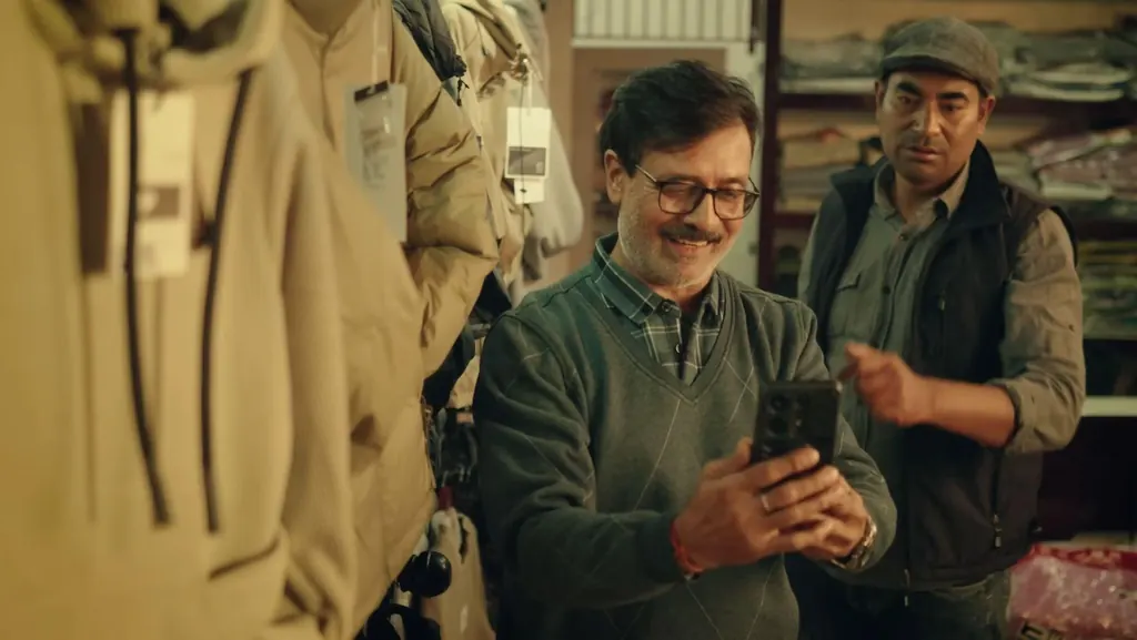 A shopkeeper filming clothes on his phone while a colleague points