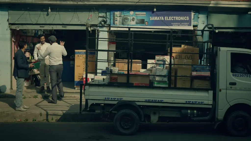 A delivery truck loaded with boxes outside an electronics shop